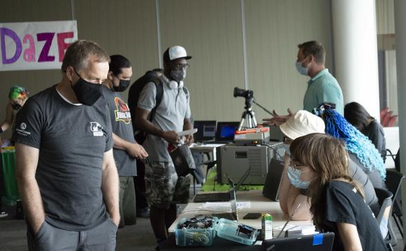 Two people talking across a table in the foreground and more people talking together in the background