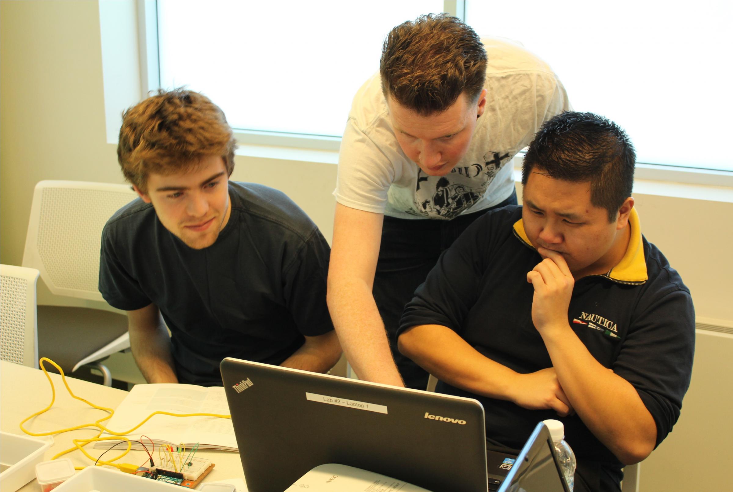 Three men looking intently at a screen