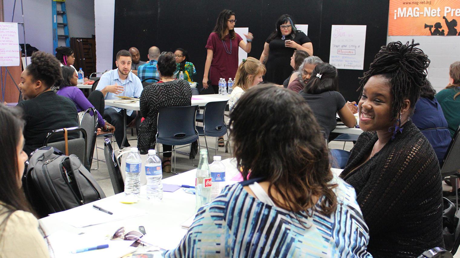a shot of the studio with rectangle tables with people on both sides having conversation